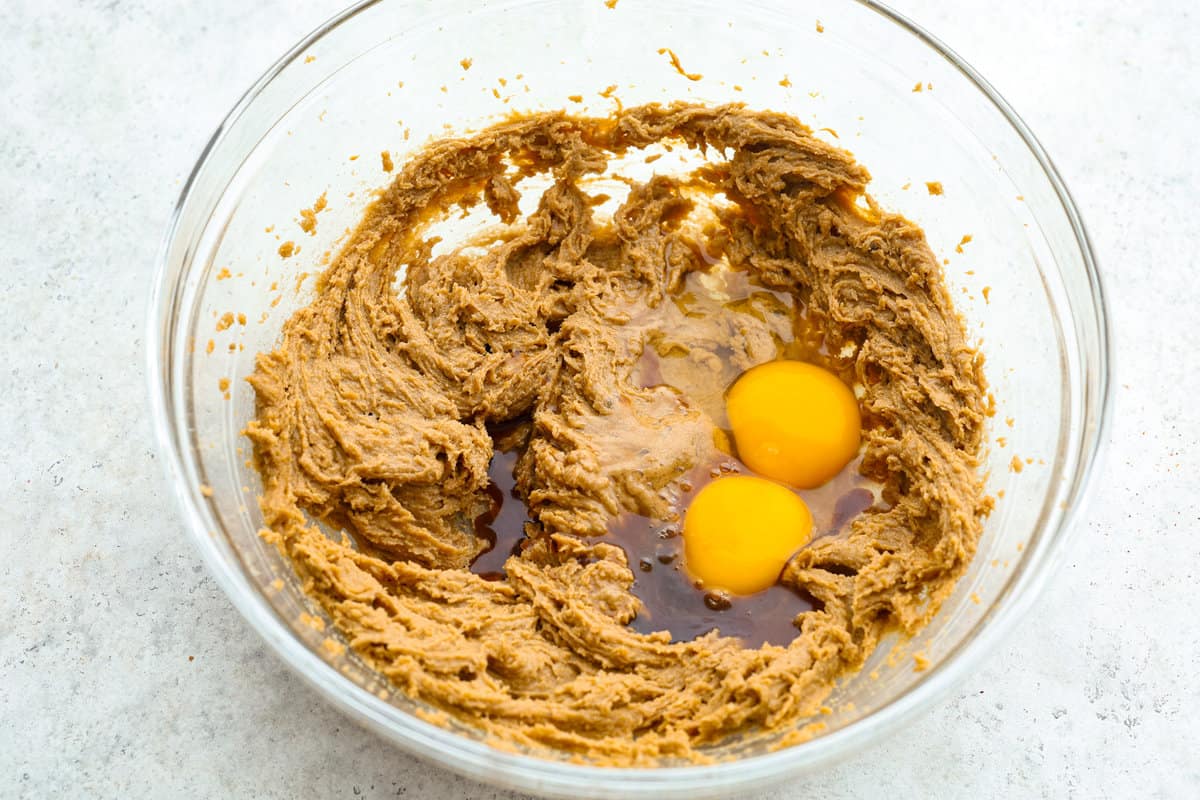 Monster cookies are slightly crisp on the outside, and soft and chewy in the center. They are loaded with peanut butter, oats, M&M candies, AND chocolate chips! Big monster cookies win every time! Process shot of eggs and vanilla added to the bowl.