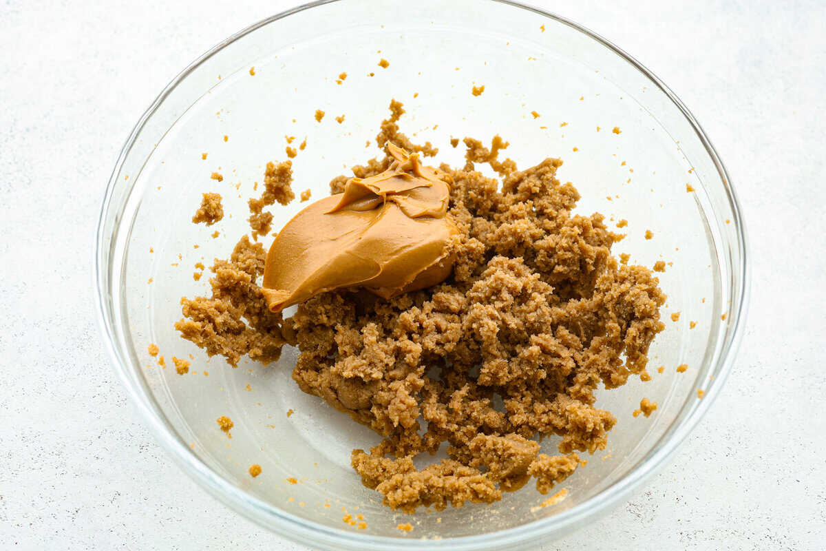 Monster cookies are slightly crisp on the outside, and soft and chewy in the center. They are loaded with peanut butter, oats, M&M candies, AND chocolate chips! Big monster cookies win every time! Process shot of peanut butter added to the creamed butter and sugars.