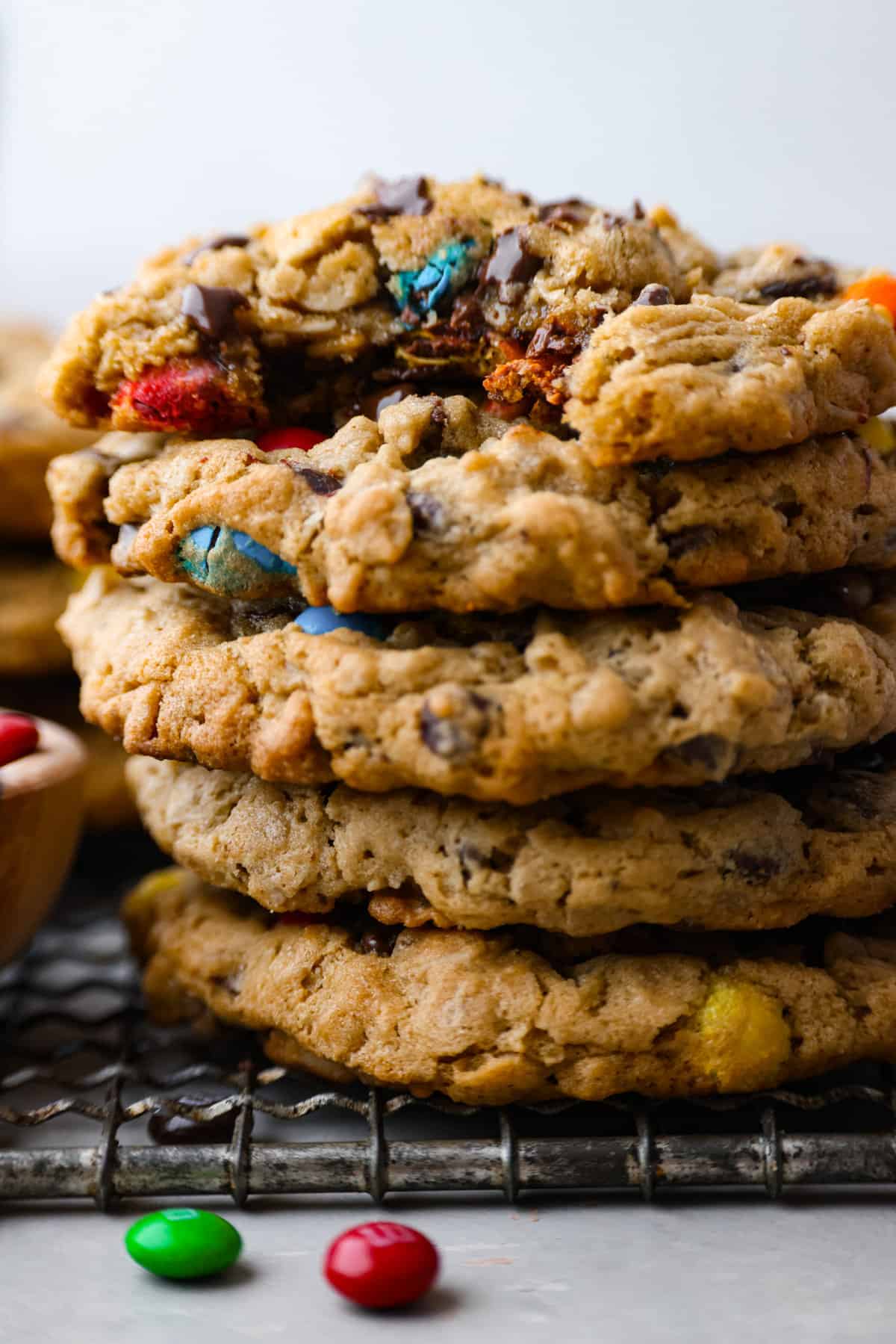 Monster cookies are slightly crisp on the outside, and soft and chewy in the center. They are loaded with peanut butter, oats, M&M candies, AND chocolate chips! Big monster cookies win every time! Close view of stacked monster cookies with a bite out of the cookie on top.
