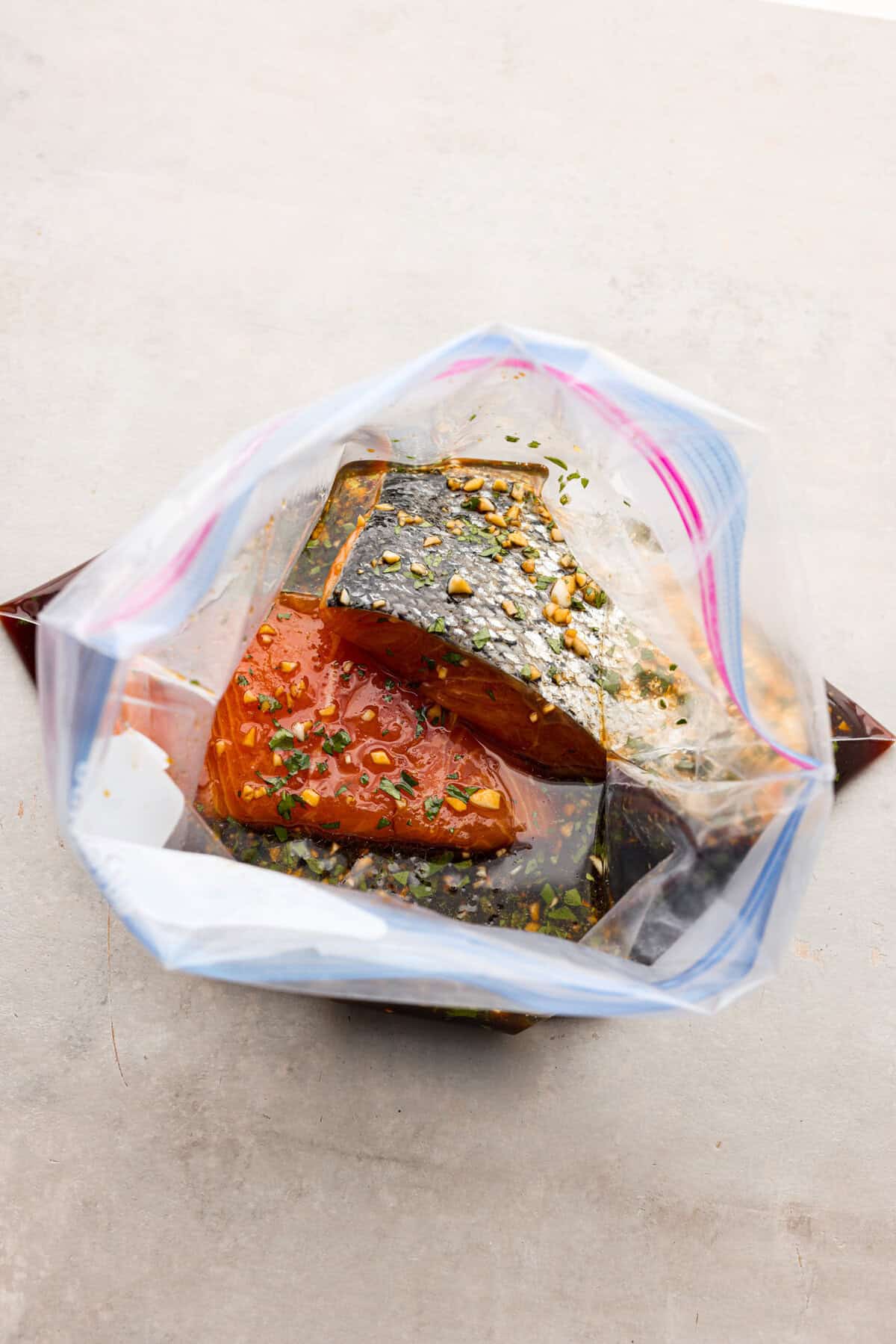 A good salmon marinade is the best way to achieve a seafood meal that's incredibly flavorful with tender, juicy fish! The top view of salmon filets in marinade in a ziplock bag.