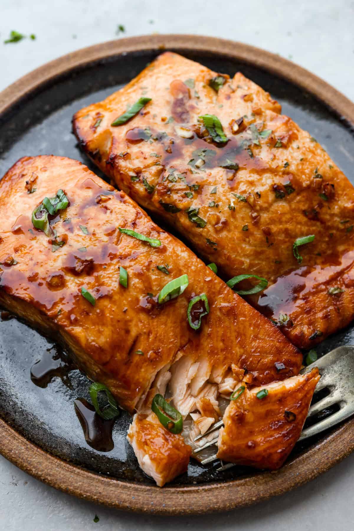 Cooked salmon filets on a plate garnished with green onions. 