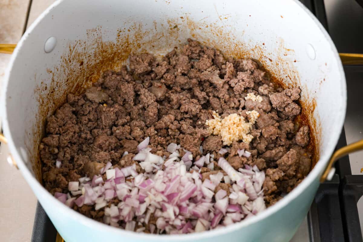 A pot filled with cooked meat, onions and garlic. 