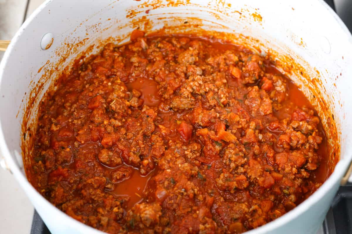Marinara meat sauce simmering in a white pot being prepared to add to the sheet pan lasagna.