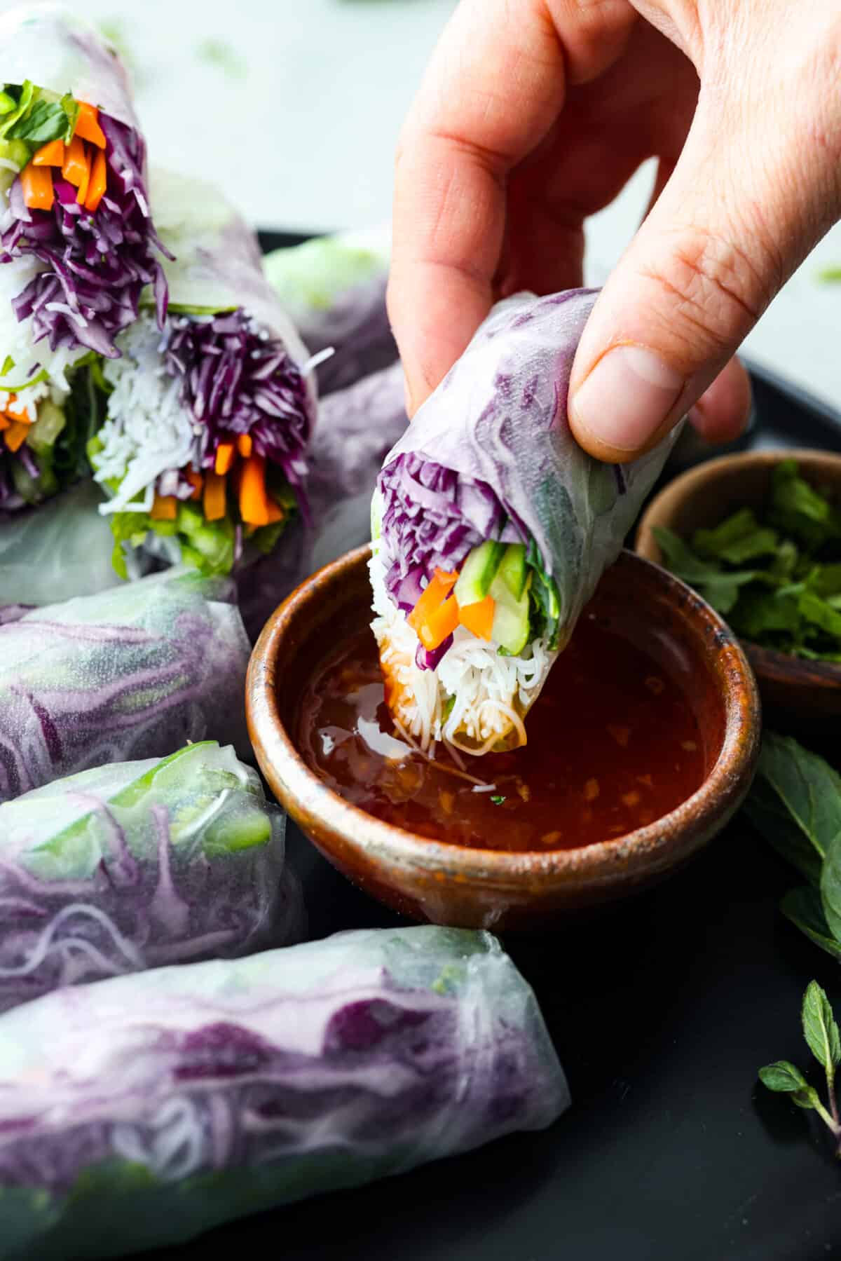 A spring roll being dipped into cili sauce. 