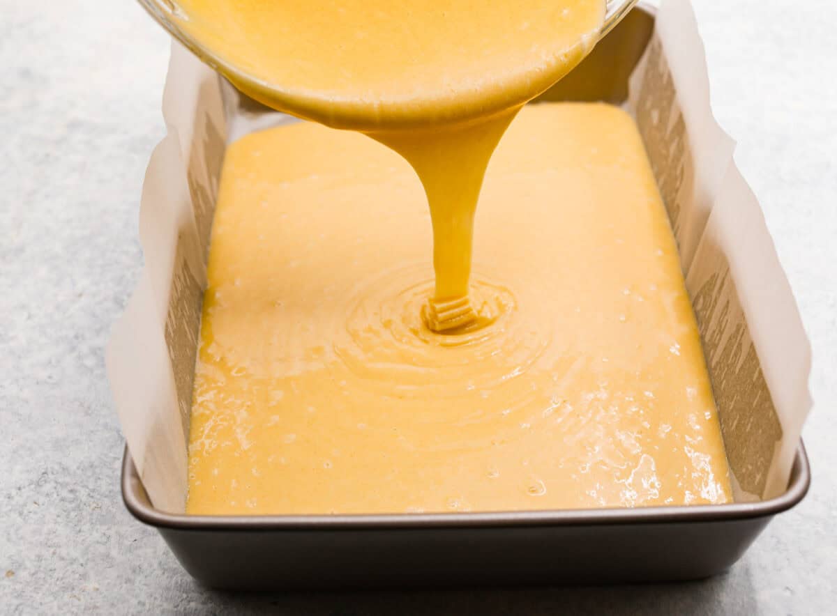 Batter being poured into a cake pan. 