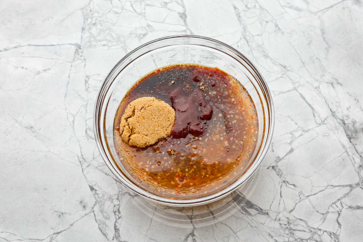 This zesty BBQ chicken is an easy crockpot recipe that only takes 5 ingredients to make! The slow-cooked tender pulled chicken is dripping in a tasty BBQ sauce. Perfect for busy weeknights or to feed a crowd! Second photo of the sauce ingredients added to a bowl.