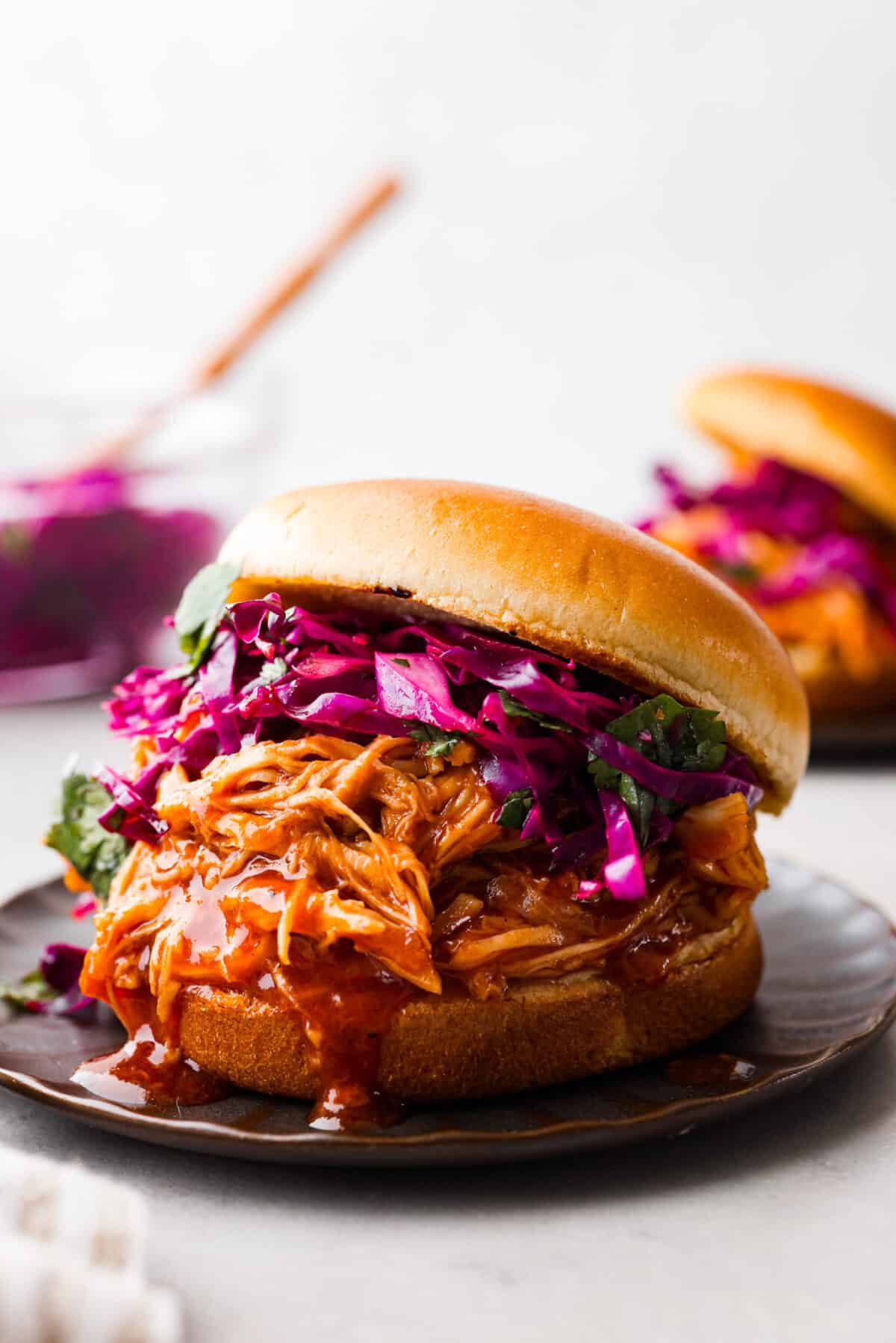 Close view of zesty bbq chicken shredded on a hamburger bun with coleslaw.
