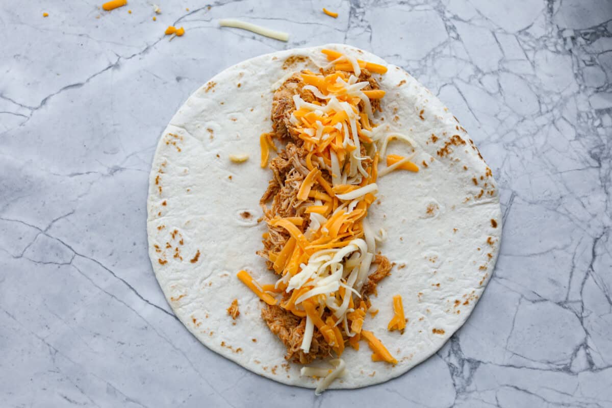 Second photo of shredded chicken and cheese added to the tortillas.