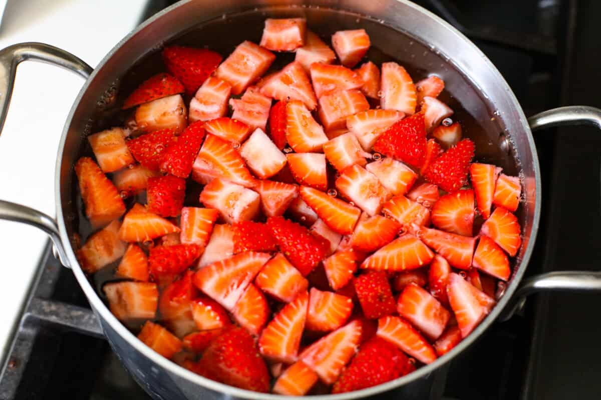 Strawberries being blanched in boiling water on the stove. 