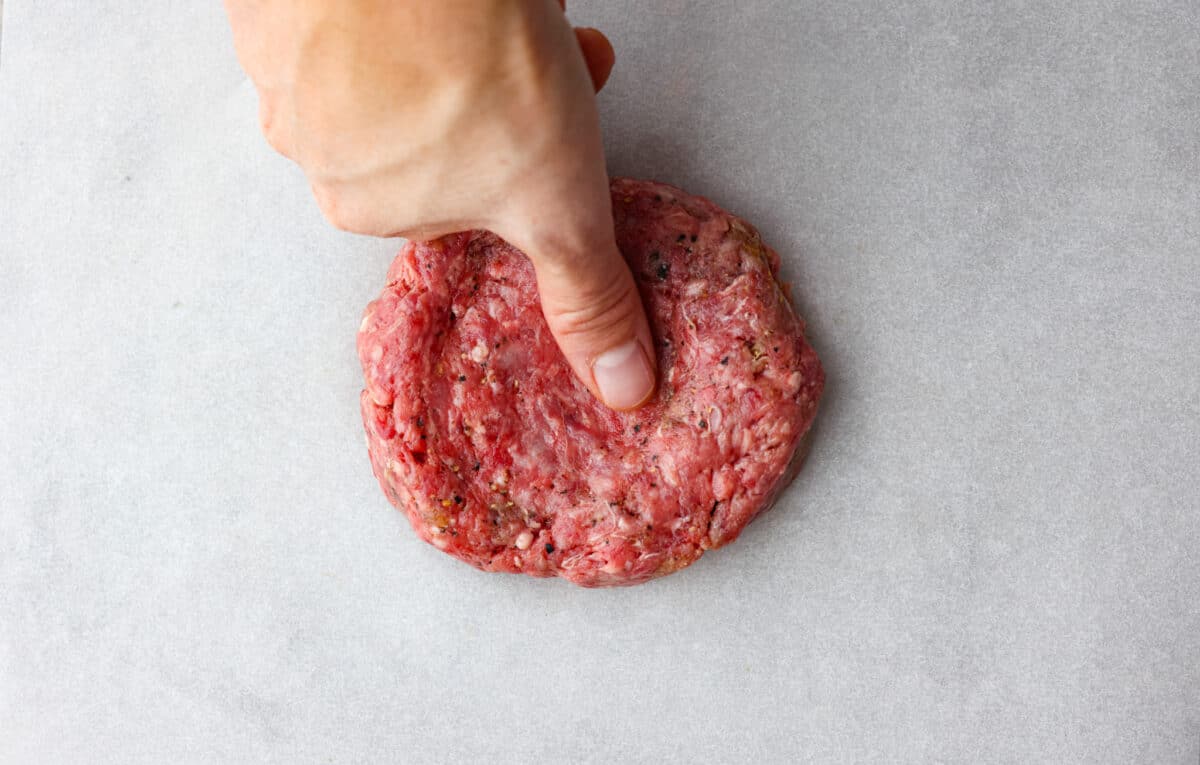 Someone indenting the ground beef with their thumb. 