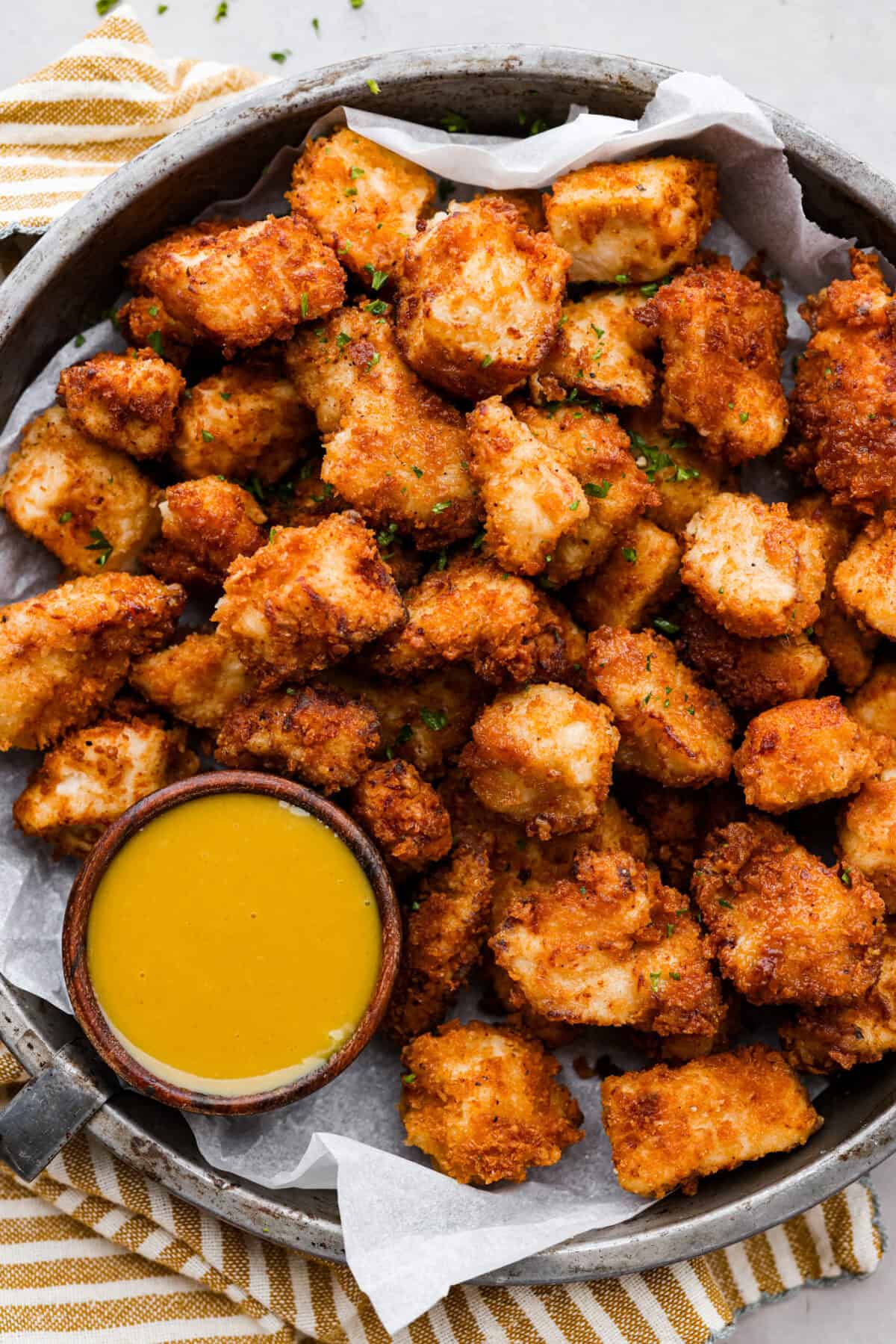 Chicken nuggets on a platter with some chick oil a sauce. 