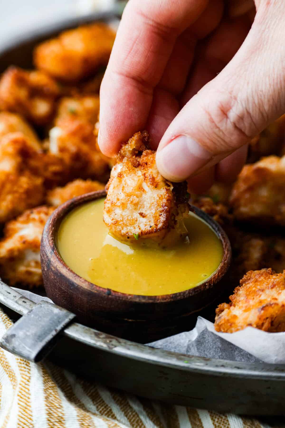 A copycat Chick-fil-A nugget being dipped in homemade chick-fil-a sauce. 