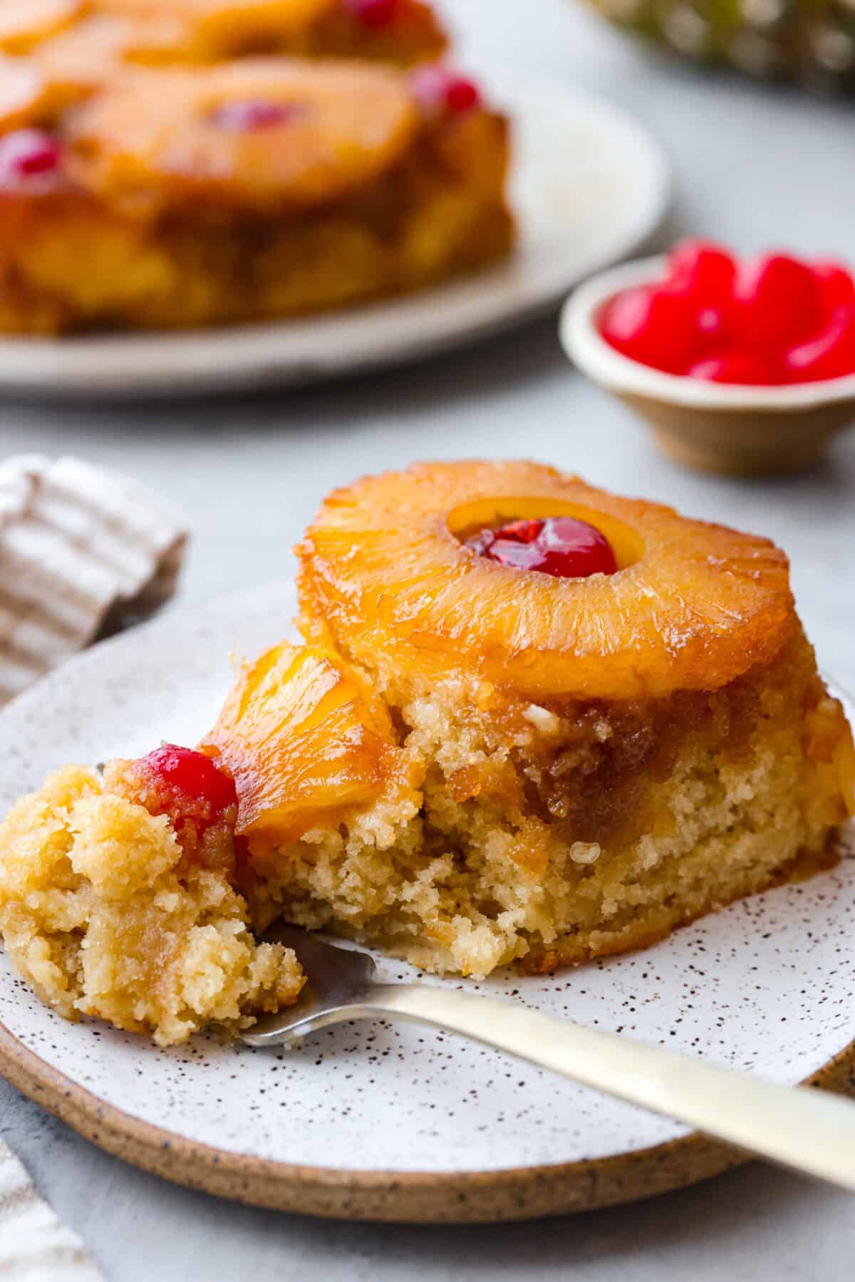 Close view of a slice of pineapple upside down cake on a plate with a fork.