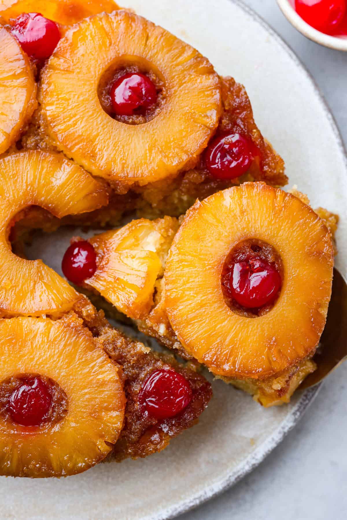 Close view of pineapple upside down cake with a slice lifting out.