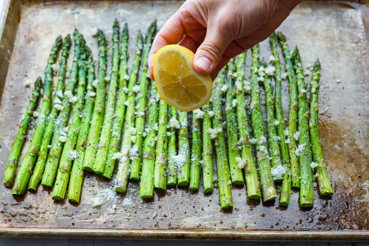 You'll love the combination of flavors in this roasted lemon parmesan garlic asparagus! It's a quick and easy side dish bursting with parmesan, garlic, and a hint of lemon to brighten it all. This is a side that you will make again and again! Fourth photo of squeezing lemon on the roasted asparagus.