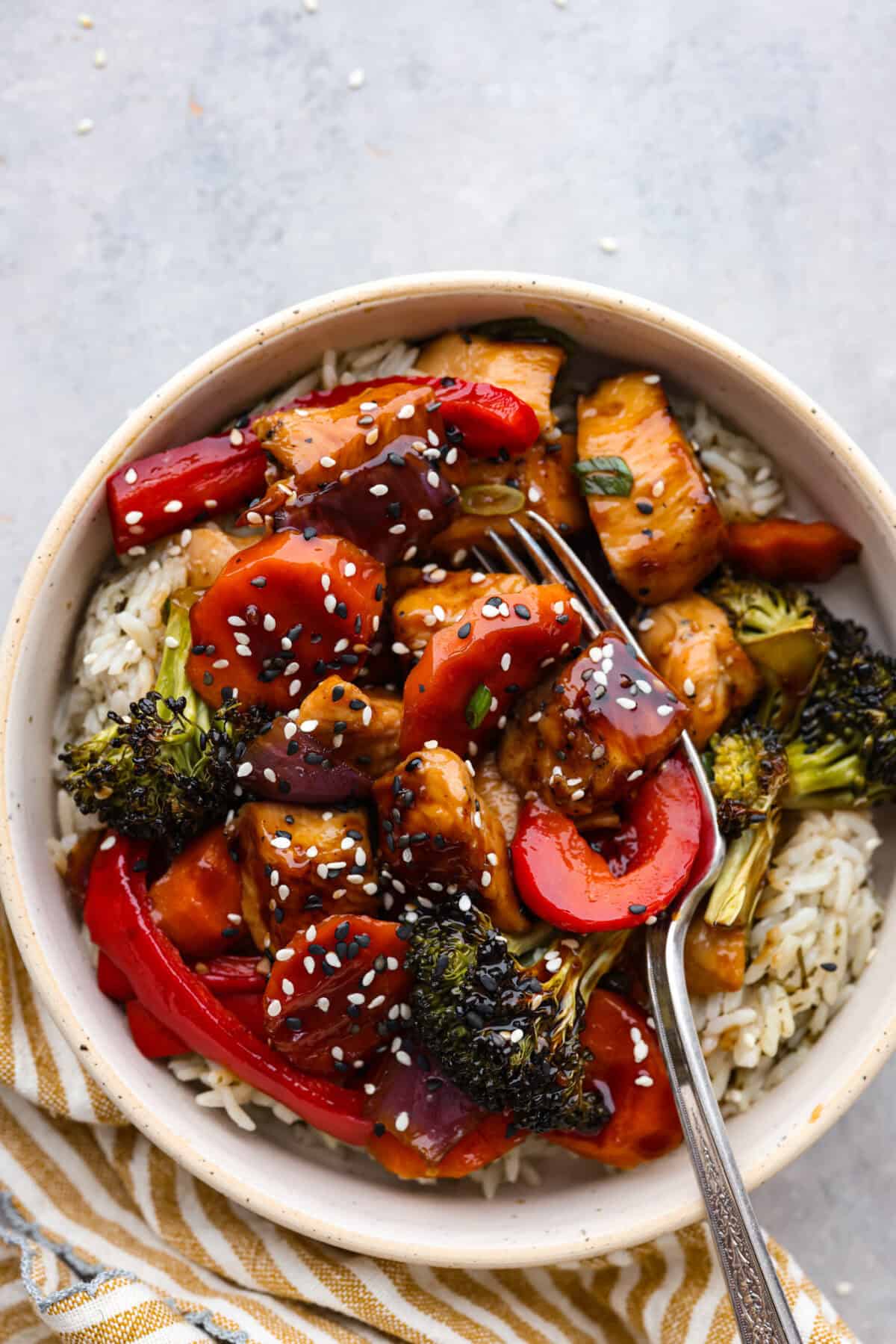 Top view of sheet pan teriyaki chicken and vegetables in a bowl over rice.