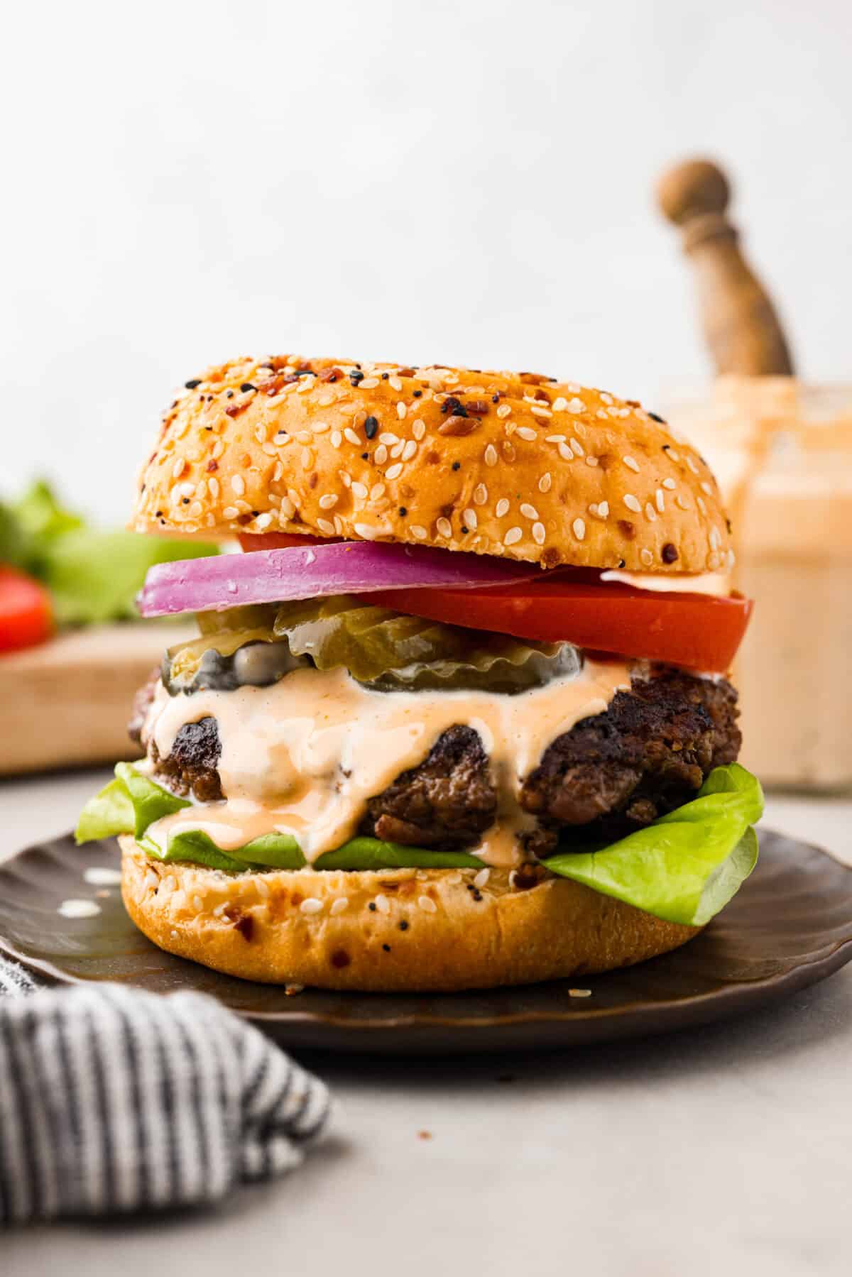 A burger ready to eat loaded with sauce and toppings. 