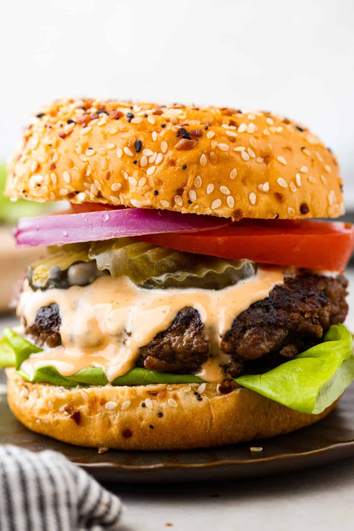 Get ready for the ultimate burger experience topped with my irresistible Secret Sauce. The flavor packed into this burger is a delicious twist on a classic favorite. A close up of a burger on a plate.