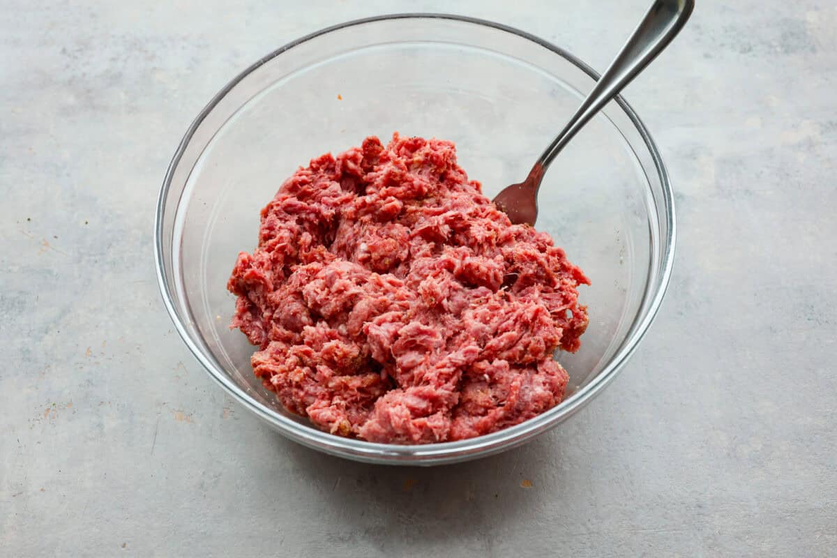 Ground beef mixed in a glass bowl. 