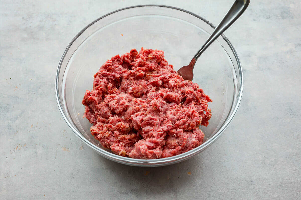 Get ready for the ultimate burger experience topped with my irresistible Secret Sauce. The flavor packed into this burger is a delicious twist on a classic favorite. Ground beef mixed in a glass bowl.