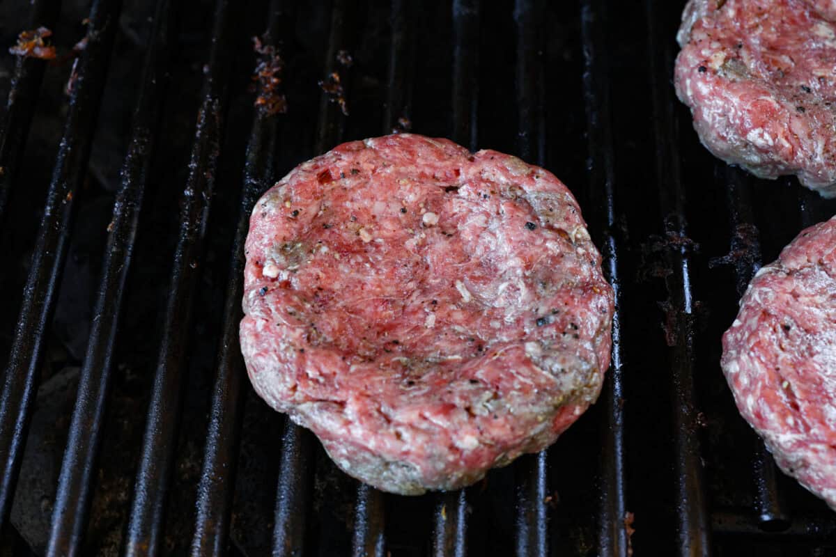 A burger patty on the grill. 