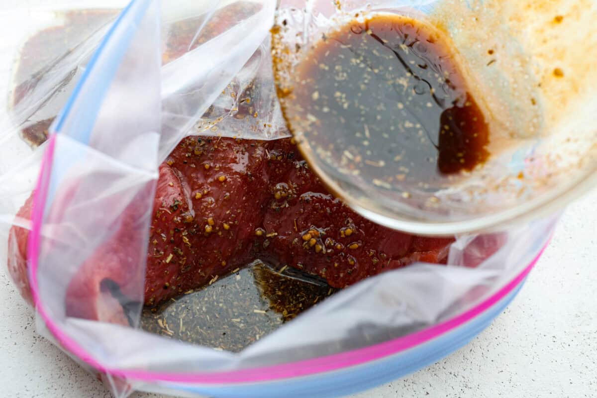Marinade being poured onto the tri tip steak in a ziplock bag. 