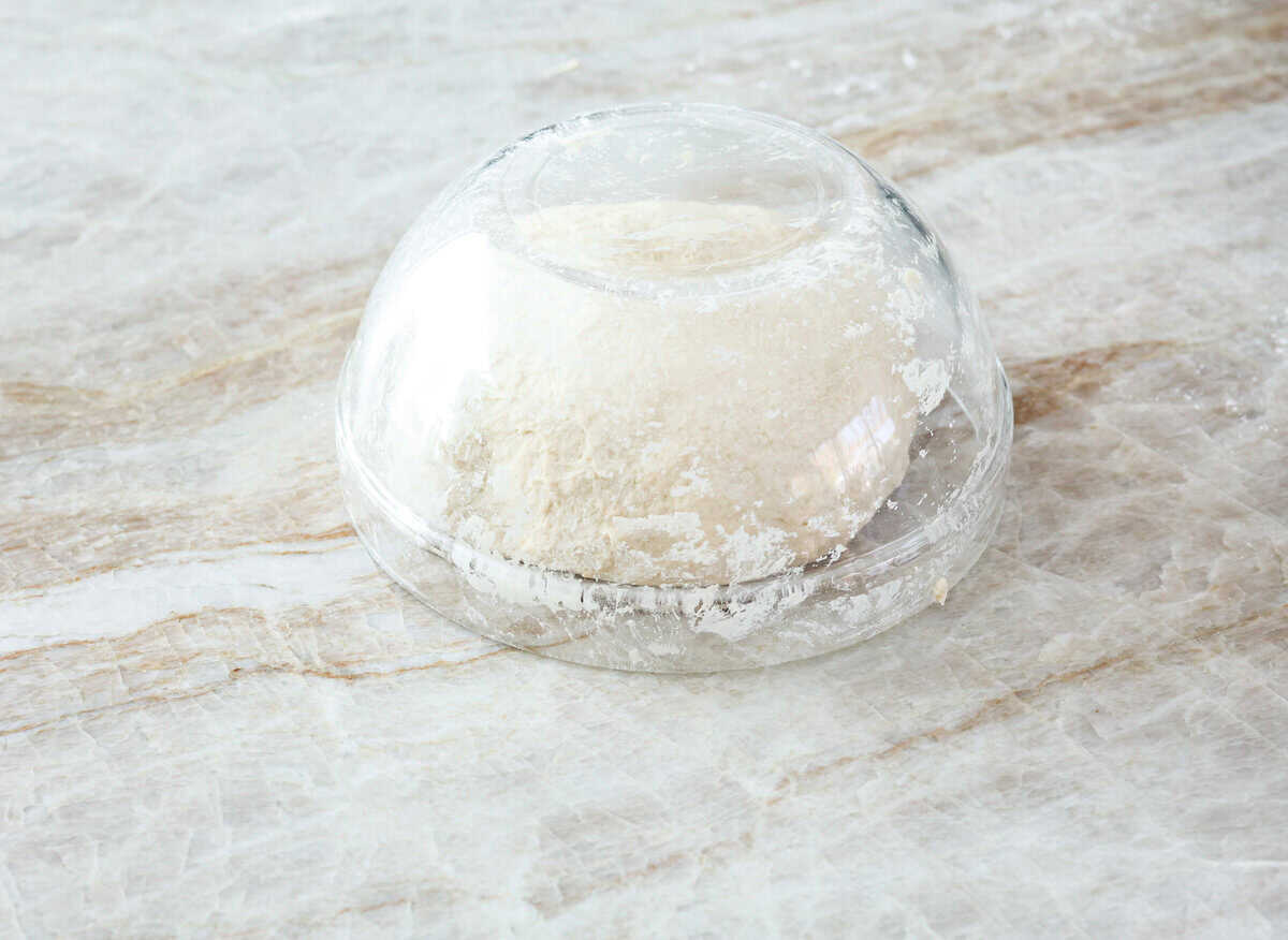 This is the perfect beginner's guide for making wood-fired pizza dough! Pizza expert, Chef Brandon Price, taught me how to make authentic homemade pizza, and now you get to learn too! Sixth photo of a glass bowl over the dough to allow it to rest.