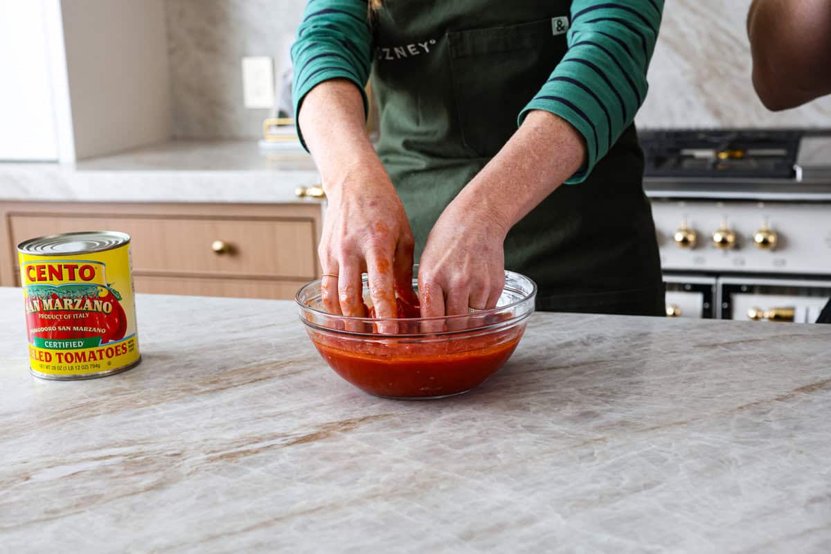 This is the perfect beginner's guide for making wood-fired pizza dough! Pizza expert, Chef Brandon Price, taught me how to make authentic homemade pizza, and now you get to learn too! Second photo of mixing the sauce with hands.