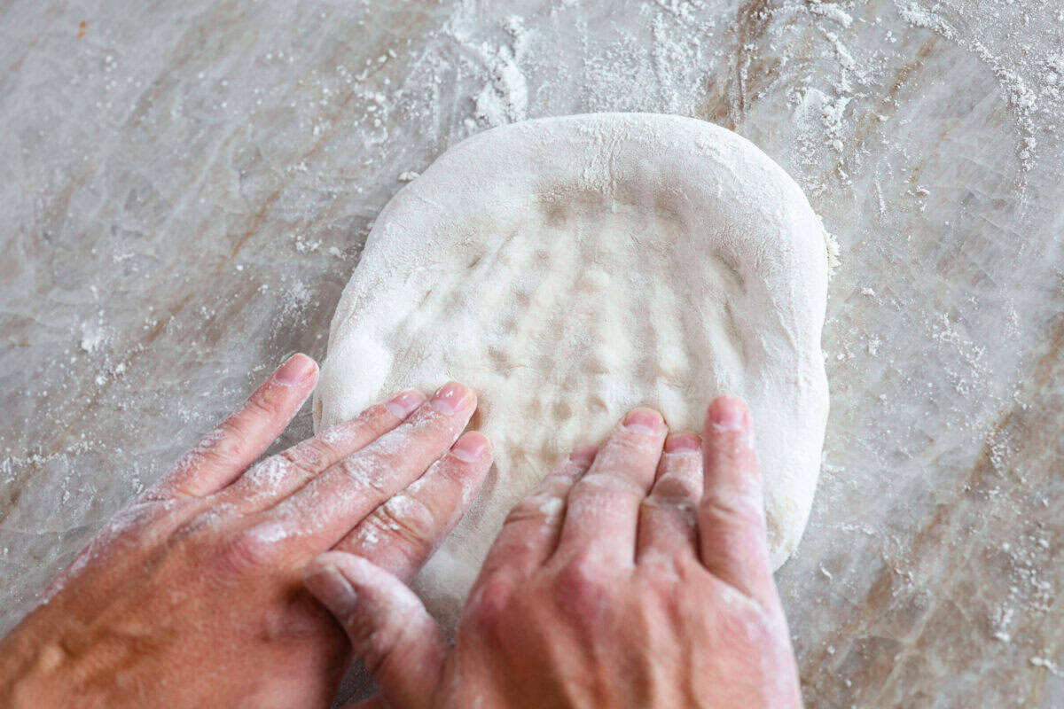 Third photo of pressing the dough to create the pizza round.