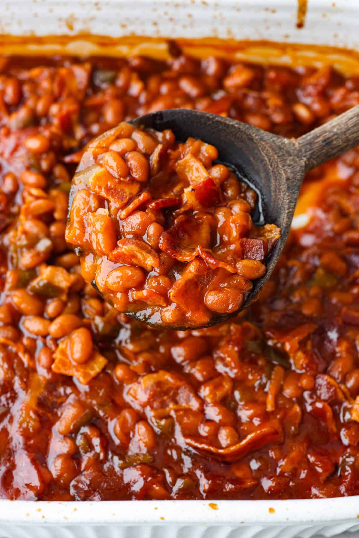 Close view of the baked beans spooned with a wooden spoon.