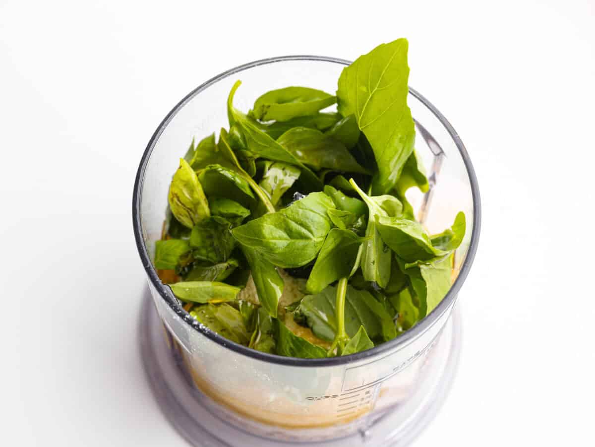 Overhead shot of all of the basil vinaigrette ingredients in a food processor. 