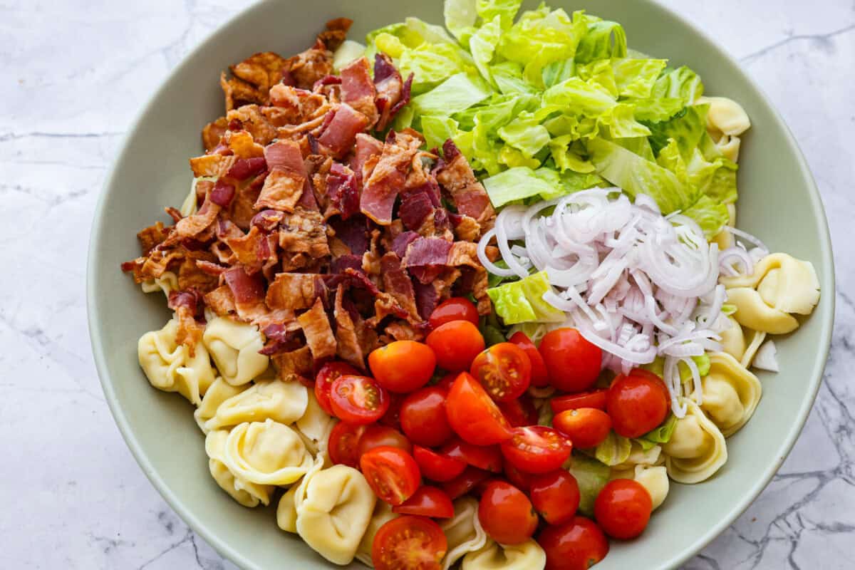 Overhead shot of all of the BLT tortellini salad ingredients in a bowl. 