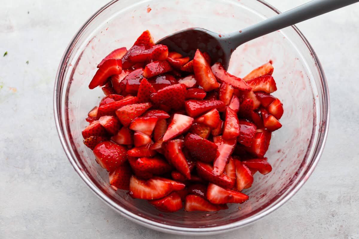 Overhead shot of a large bowl of strawberries being stirred. 