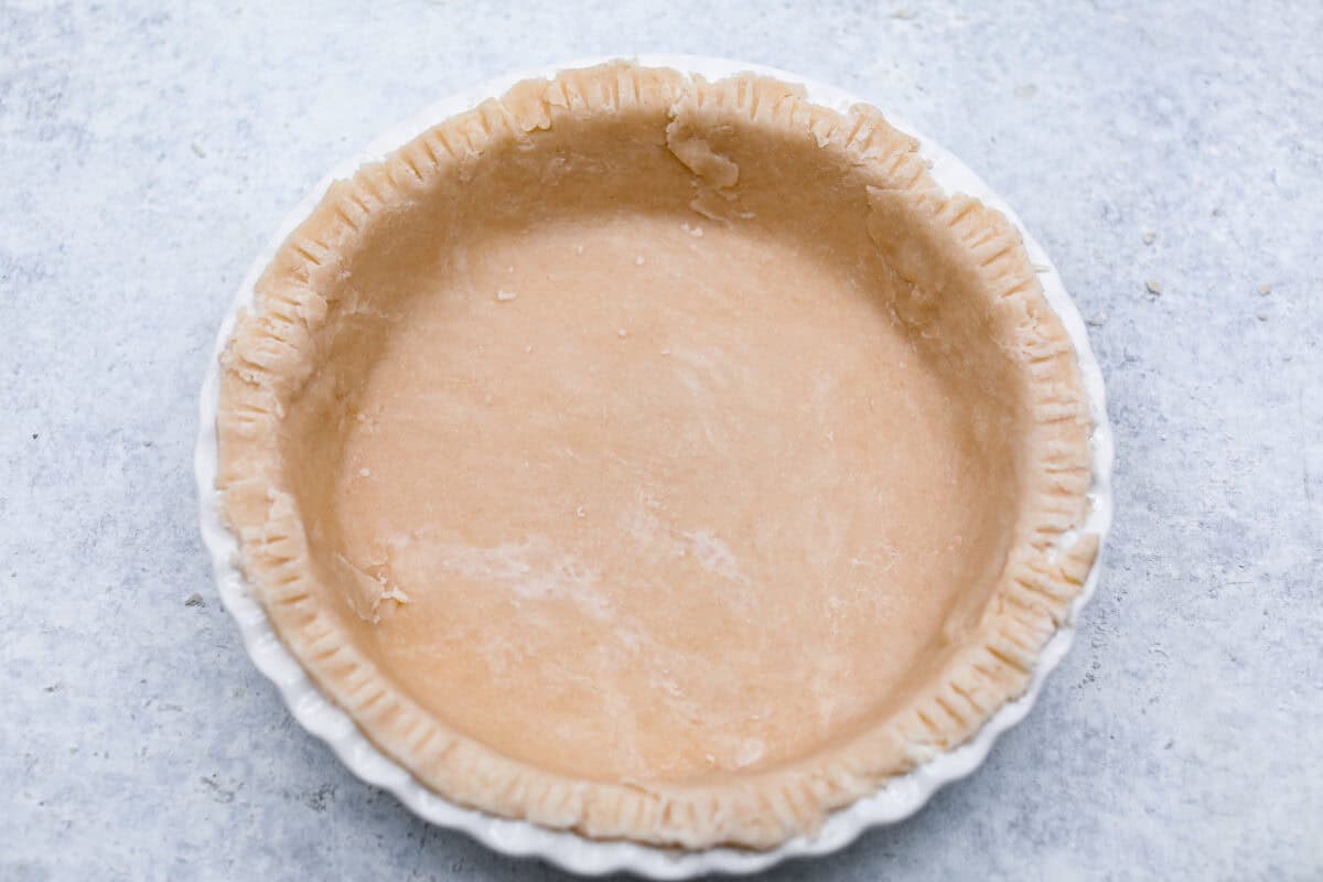 Overhead shot of pie crust crimped edges in a pie pan. 