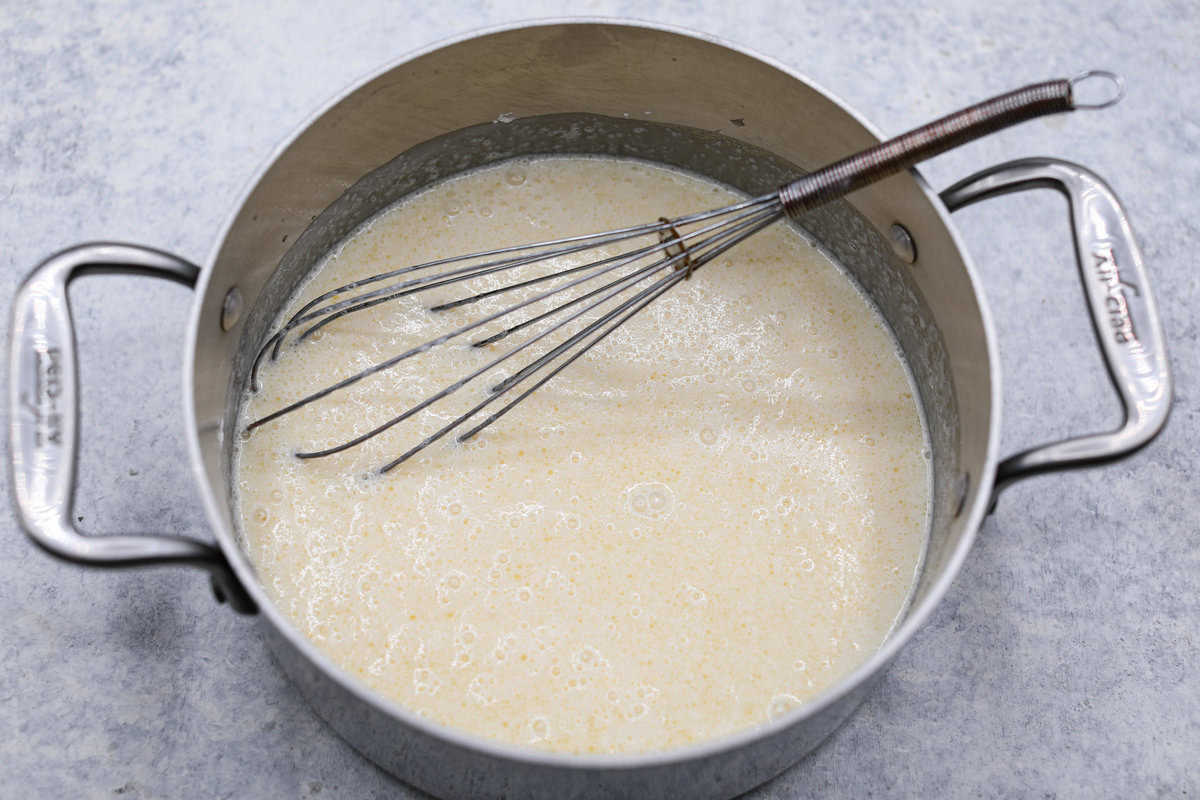 Sugar cream pie, or Hoosier pie, is a creamy, delicious treat with deep roots in the Midwest, especially in Indiana. You can top it however you like, serve it warm, at room temperature, or even chilled. Give this simple recipe a go. I know you’ll love it! Overhead shot of pie filling ingredients in a pot with a whisk.
