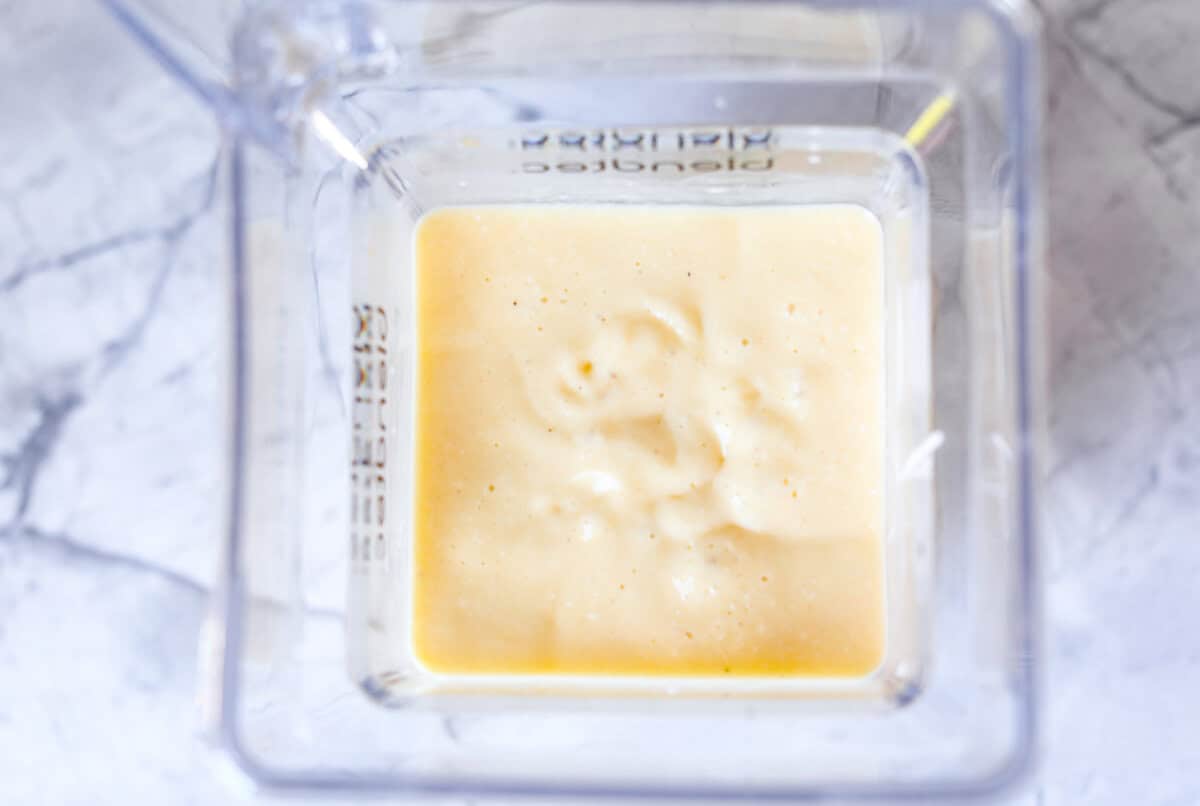 This refreshing tropical smoothie is bursting with tropical fruit flavors, making it the perfect treat for a hot day. Sip it, and you'll feel like you're lounging on the beach, enjoying a drink freshly served by the cabana boy! Overhead shot of blended up tropical smoothie ingredients.