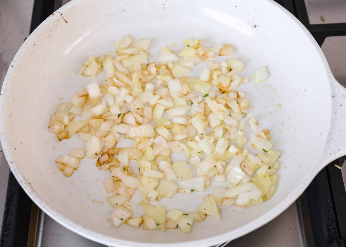 Angle shot of diced onions being sautéed in a skillet. 