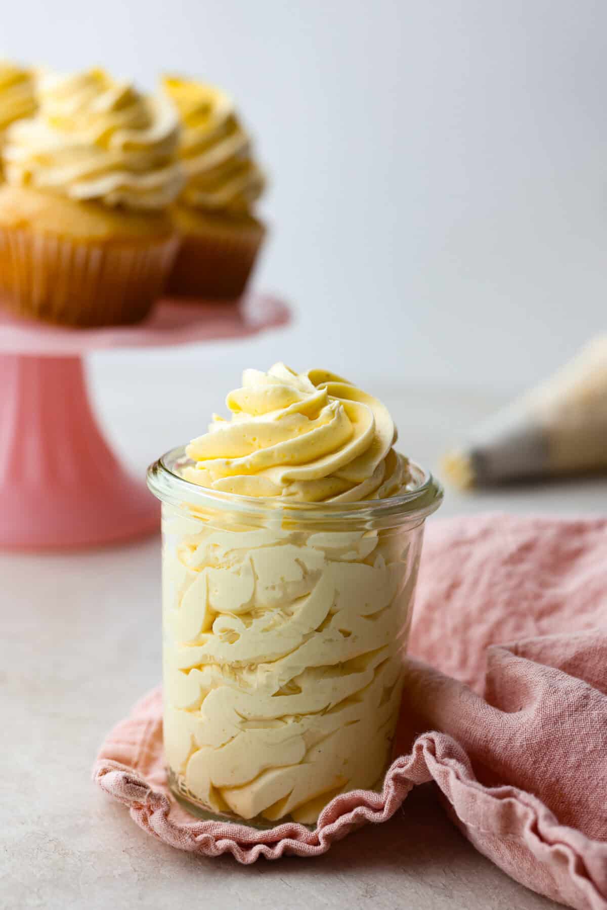 Side shot of french buttercream piped into a small glass jar. 