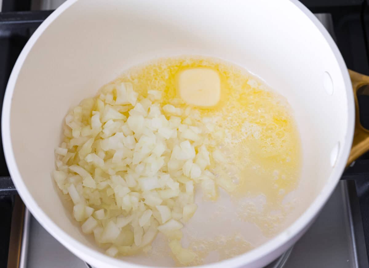 Overhead shot of melted butter and onions in a pot on the stove.