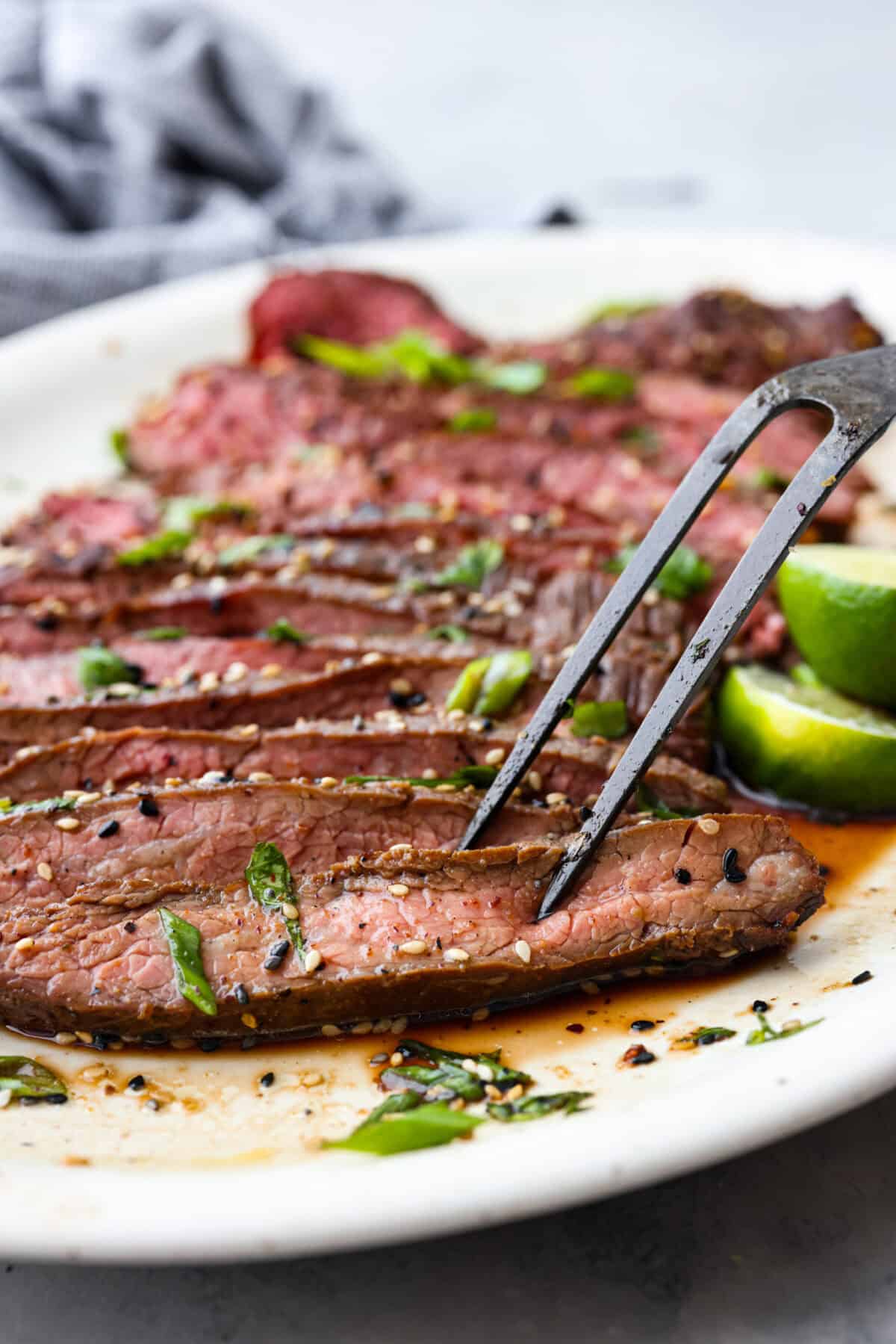 Close up shot of large fork skewering slice of steak. 