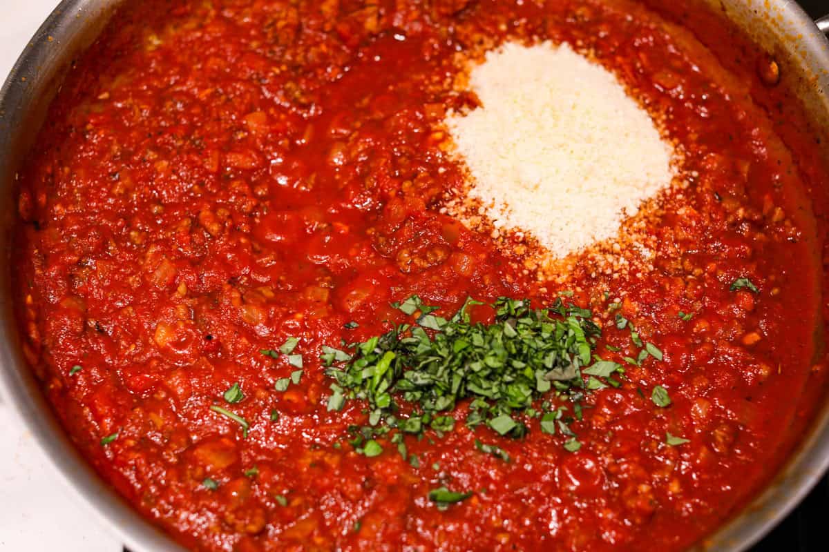 There's no need to purchase store-bought sauce, with this hearty and flavorful Homemade Spaghetti Sauce. Simple ingredients such as ground beef, onion, garlic, and spices of oregano and basil bring a bold flavor to this simple sauce. Fourth photo of the cheese and basil added to the sauce.