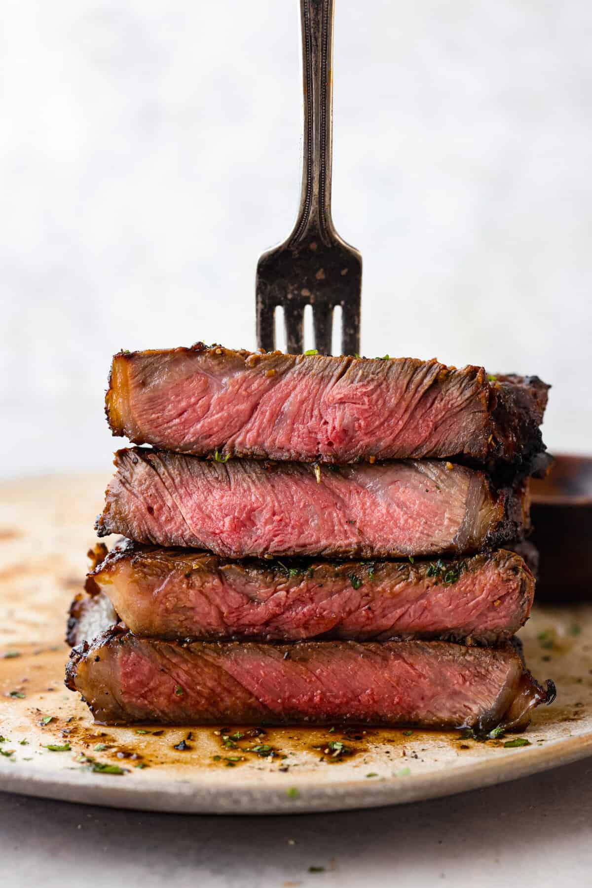 Learn the basics of using meat in the kitchen! I walk you through the different cuts of meat and help you feel confident with your delicious meat recipes. You will LOVE this helpful guide to understanding beef, pork, and chicken! Close view of grilled stacked pieces of steak with a fork stabbing in the meat on top.
