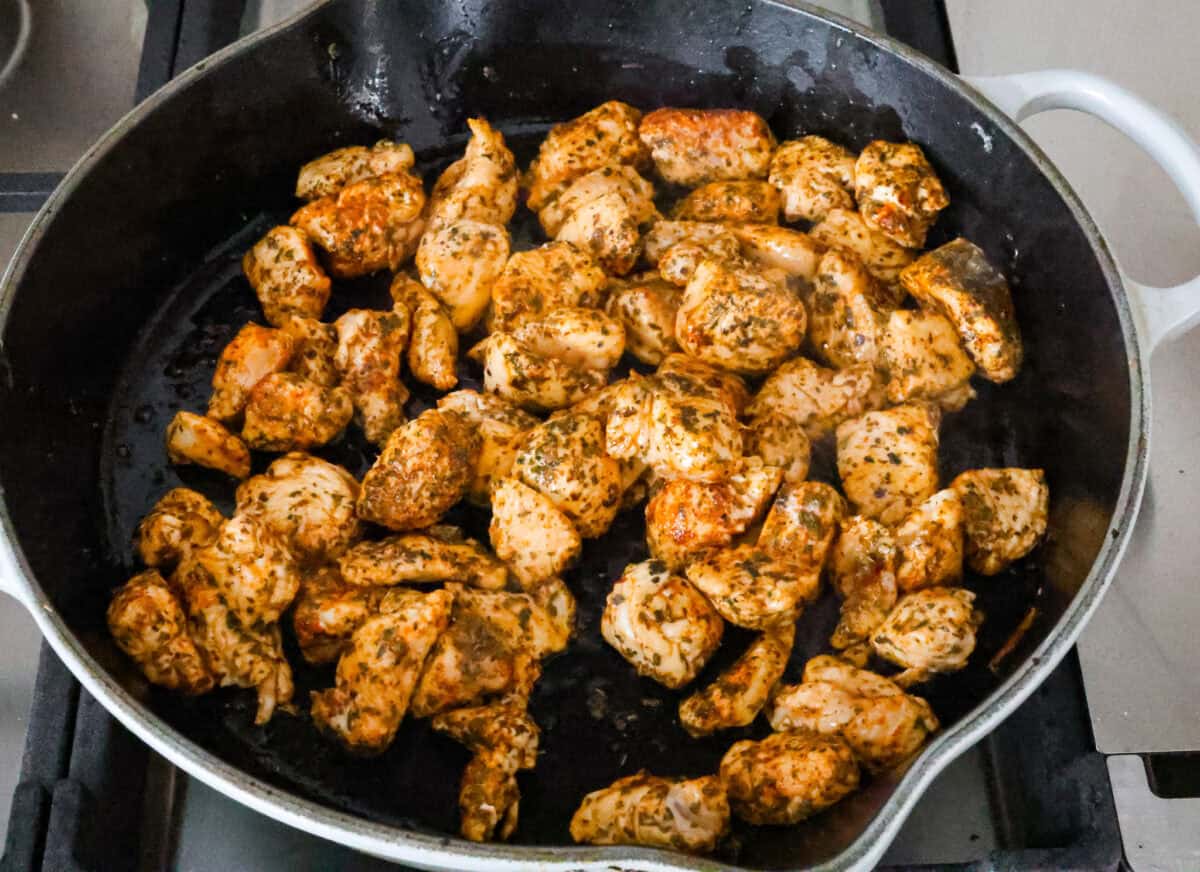 Angle shot of pieces of seasoned chicken being seared in a pan.