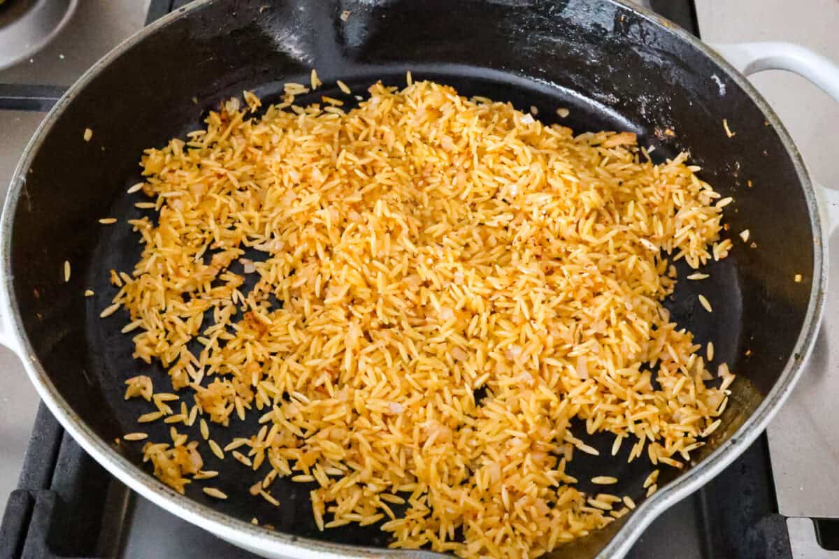 Angle shot of orzo pasta being browned in a pan. 