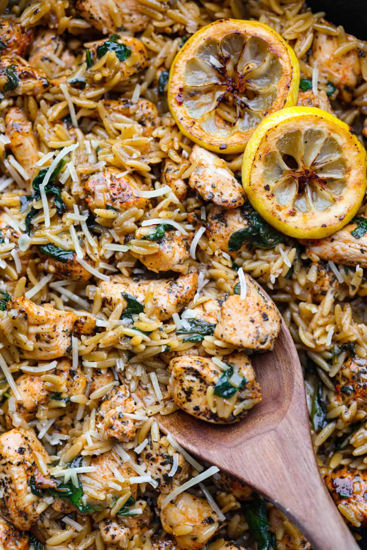 Close up shot of chicken lemon orzo with wooden spoon.  