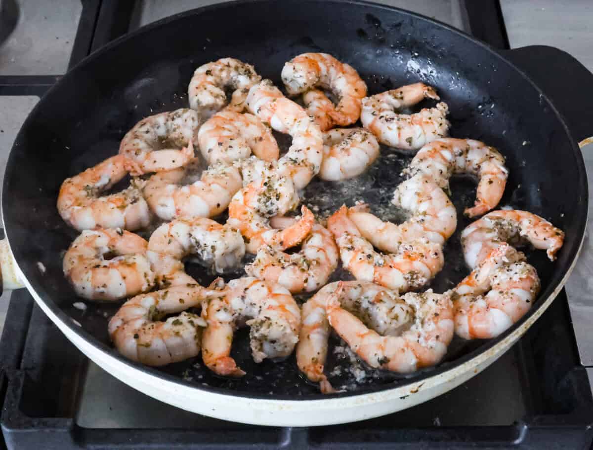 Angle shot of seasoned shrimp being cooked in a skillet. 