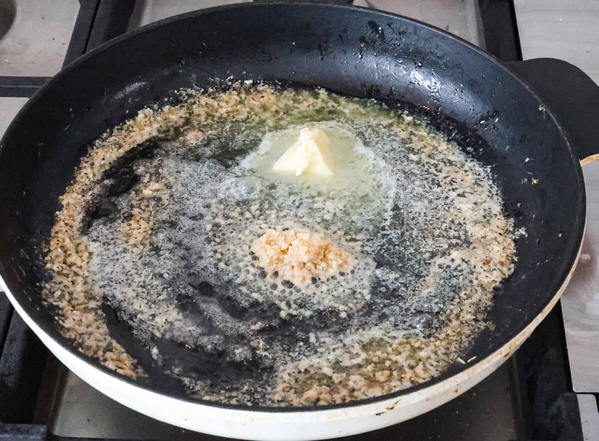 Marry Me Shrimp Pasta dazzles with robust Italian flavors. It's ready in just 30 minutes, and the creamy sauce, brimming with fresh herbs and spices, could very well lead to a marriage proposal after your first bite! Angle shot of but and garlic sautéing in a skillet.