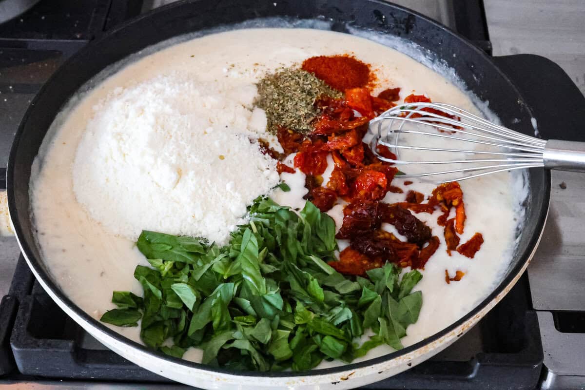 Marry Me Shrimp Pasta dazzles with robust Italian flavors. It's ready in just 30 minutes, and the creamy sauce, brimming with fresh herbs and spices, could very well lead to a marriage proposal after your first bite! Angle shot of skillet with sauce, basil, sun-dried tomatoes, parmesan and seasonings.