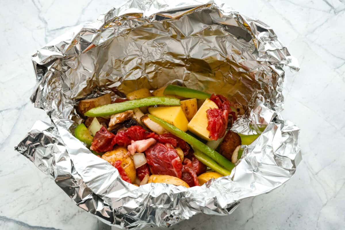 Overhead shot of foil with raw meat and veggie mixture in it. 
