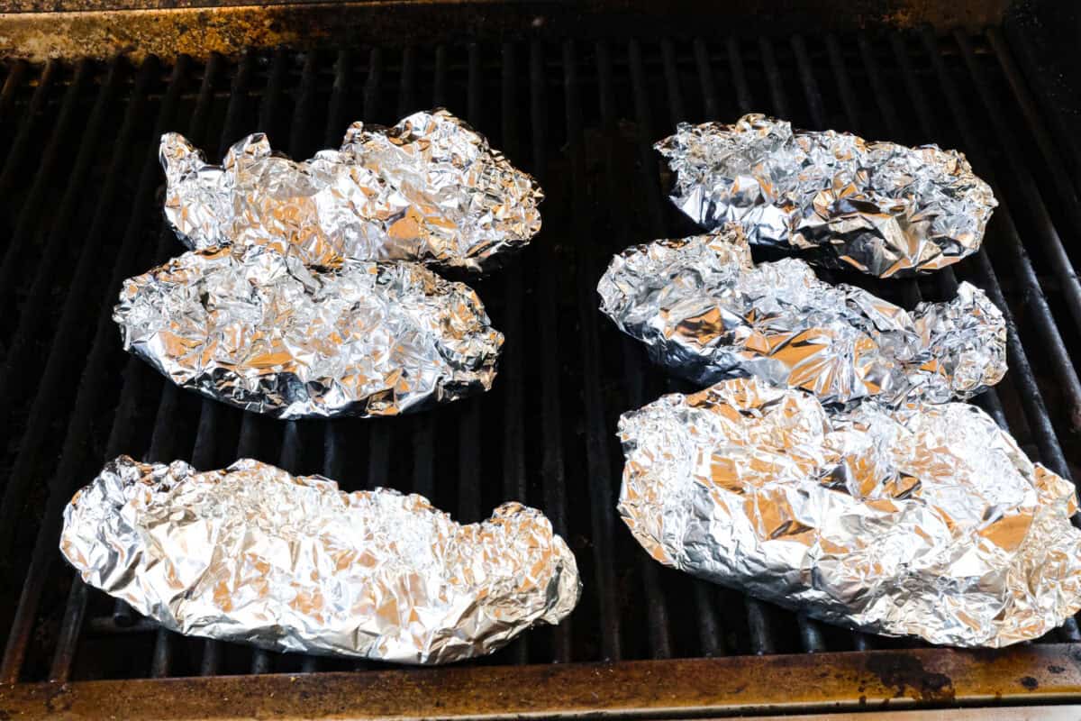 Angle shot of wrapped philly cheesesteak packs on grill. 